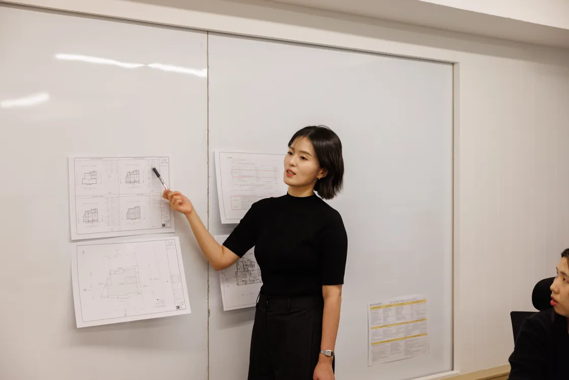 화이트보드에 붙인 도면을 짚으며 설명하는 김유나 대표