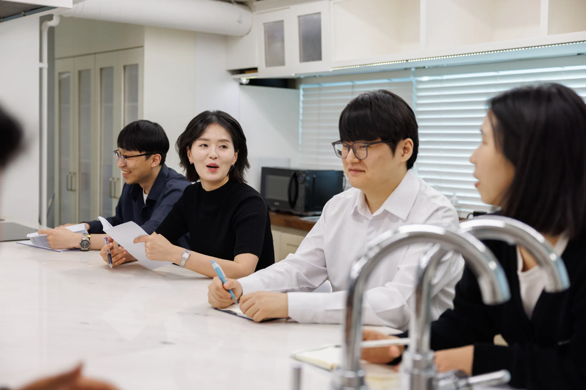 큰 탁자에 둘러앉아 웃으며 이야기하는 김유나 대표와 직원들